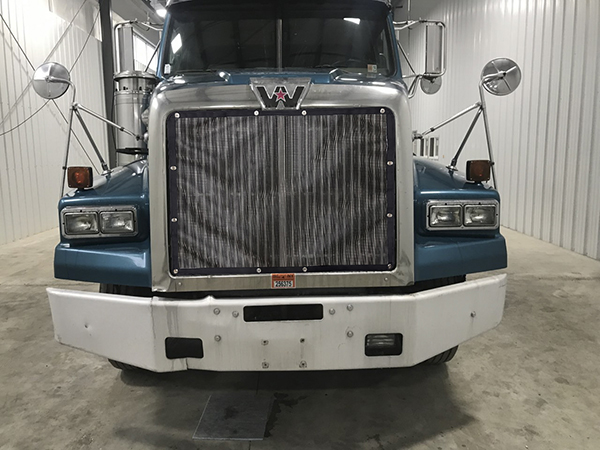 A blue truck parked in a garage with its front end.