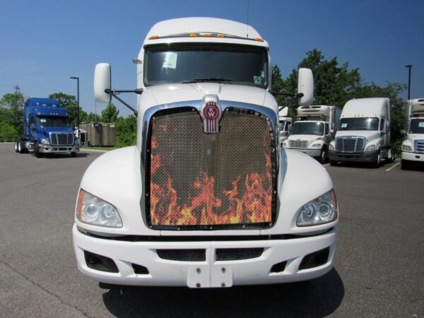 White semi-truck with Bug Screen: Flames design on the grill parked in a lot with other trucks in the background.