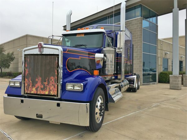 Customized blue semi-truck with Bug Screen: Flames detailing parked in front of a building.