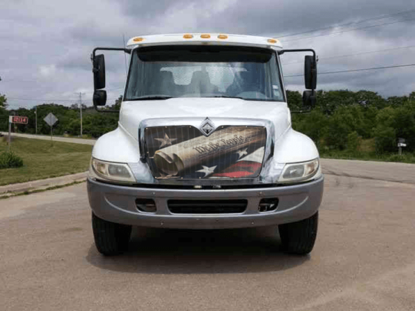 Front view of a white semi-truck parked on a road with the We The People - Bug Screen installed.