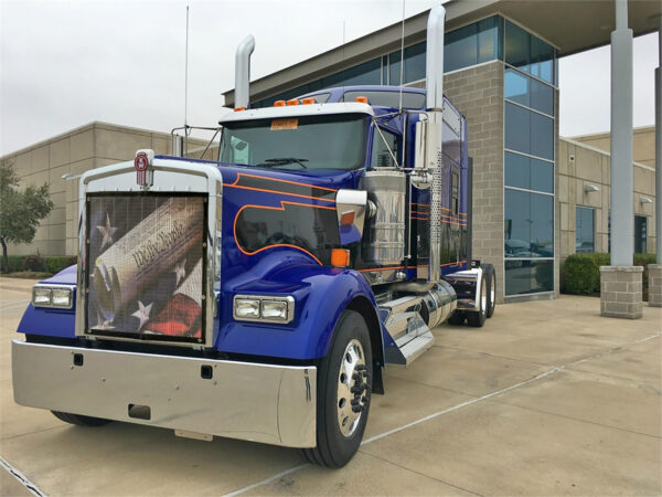 A blue semi-truck with an orange and gray design parked in front of a building.