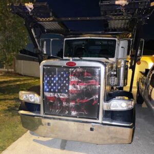 Semi-truck at night adorned with a Smokey Flag-Bug Screen on its grille.