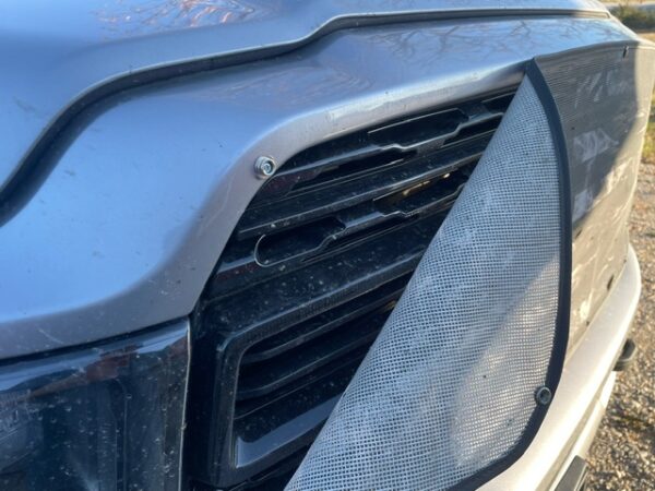Close-up of a car's headlight and grille covered in dust and pollen with a Pickup/SUV/Van Bug Screen: Plain.