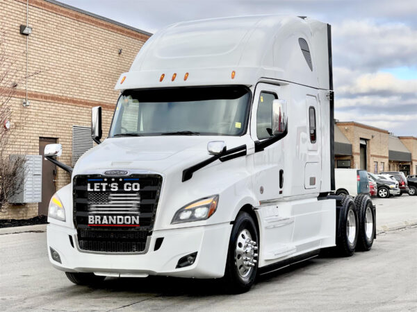 A Let's Go Brandon! - Semi Truck Mesh Bug Screen parked on a concrete area with a customized front grille message.