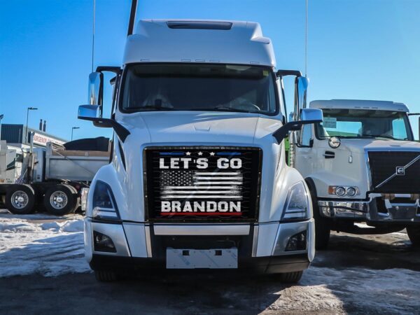 Let's Go Brandon! - Semi Truck Mesh Bug Screen with "let's go brandon" sign on the grille, parked in a lot with snow and other trucks in the background.