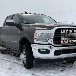 A grey ram pickup truck parked on a snowy terrain with a Let's Go Brandon!- Pickup/Suv/Van Mesh Bug Screen displaying the phrase "let's go brandon".