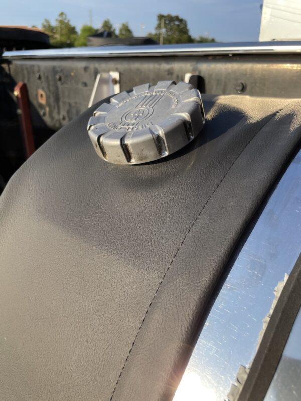 Fuel Tank End Cover on top of a vehicle's fender against a clear sky.