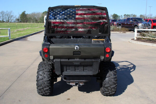 A military style utility vehicle with an american flag on the back.