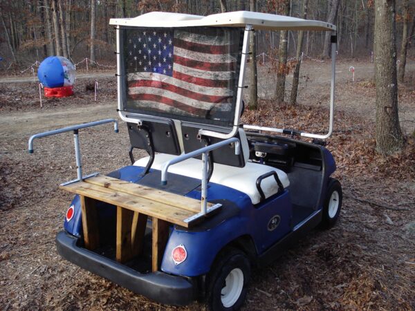 Golf cart adorned with an american flag, featuring a UTV/Side by Side Rear Dust Screen and rear lights.