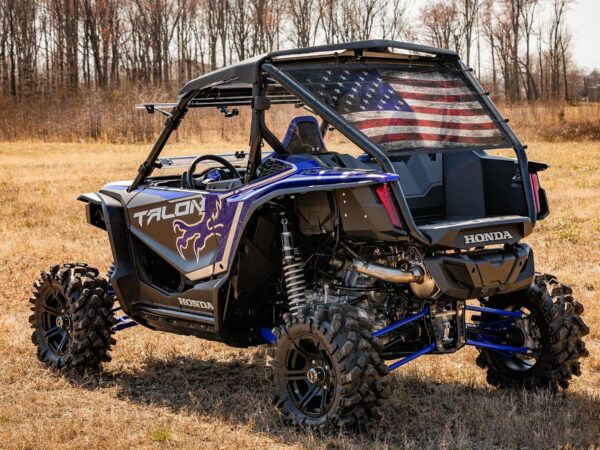 A UTV/Side by Side Rear Dust Screen off-road vehicle parked in a dry grassy field, displaying an american flag on the back.