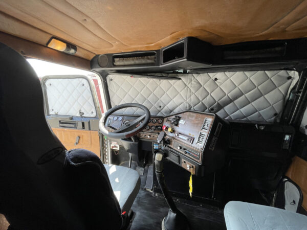Interior of a vintage vehicle with ZenEclipse Premium Window Covers for Semi Trucks on the dashboard, steering wheel, and door panels.