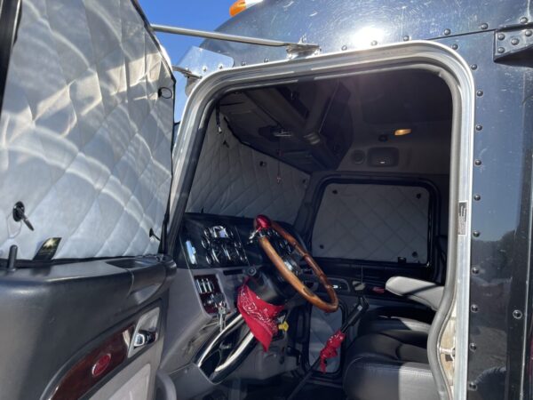 Interior view of a classic vehicle with a wooden steering wheel and a red bandana on it, showcasing ZenEclipse Premium Window Covers for Semi Trucks.