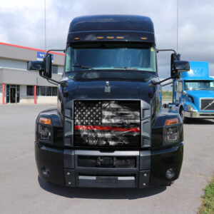 Front view of a black semi-truck with a Thin Red Line - Bug Screen design on the grille, parked in a lot with other trucks in the background.