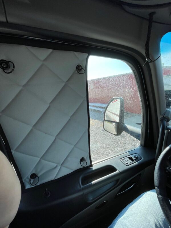 Driver's side window covered with ZenEclipse SunBlocker material, obstructing the view, while the vehicle is on the road.