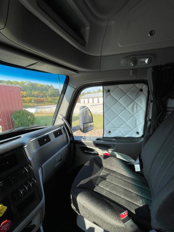 Interior view of a truck cabin with a ZenEclipse SunBlocker drawn back and a side mirror visible.
