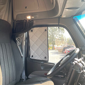 Interior of a truck cabin with sunlight streaming through the window, featuring upholstered driver's seat and a ZenEclipse SunBlocker on the side window.