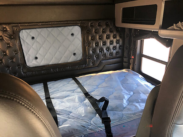 Interior view of a sleeper cabin in a truck featuring ZenEclipse Sleeper Covers for Kenworth and a bed with protective plastic covering.