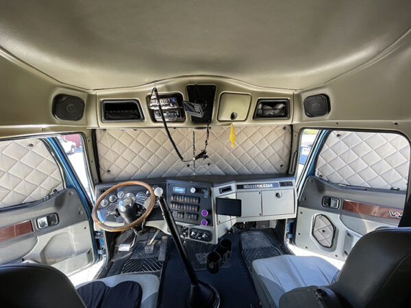 Interior of a ZenEclipse for Western Star featuring a diamond-patterned upholstery, a classic steering wheel, and an old-fashioned dashboard with multiple gauges and controls.