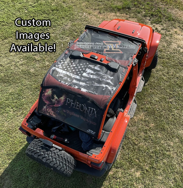 A customized red Jeep Wrangler JL (2018-2023) with a black TopLess Tops featuring graphic designs on a grass field.