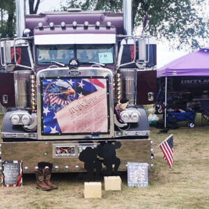 A purple truck with an american flag on the front.