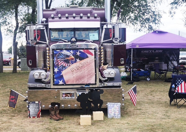 A purple truck with an american flag on the front.