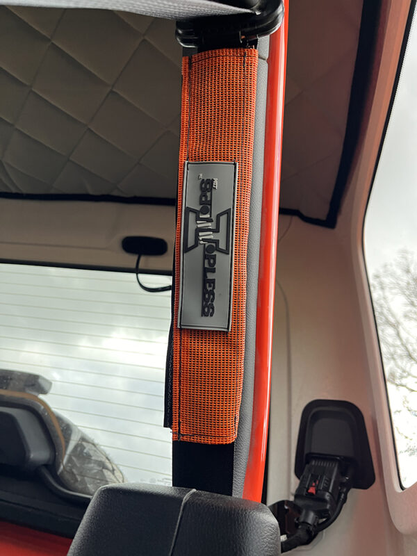 A close up of the door handle on an orange truck.