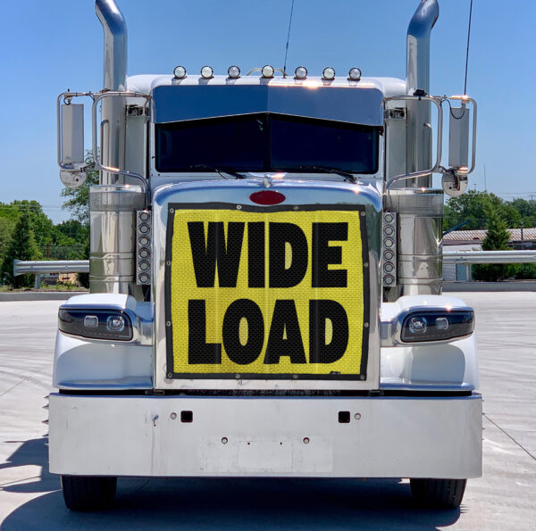 Front view of a white semi-truck with a Bug Screen: Wide Load attached to its grille.