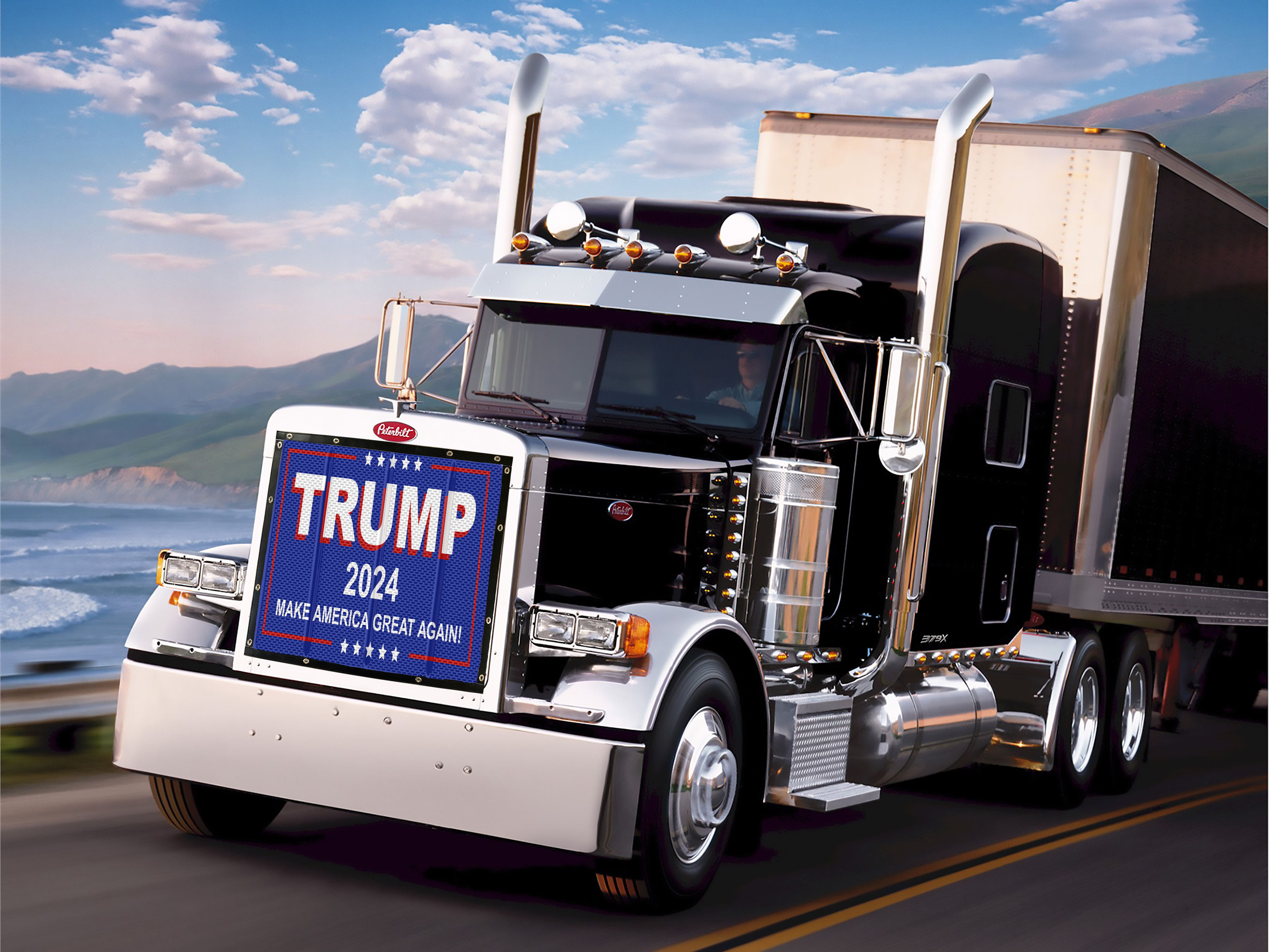 A black semi-truck with a Bug Screen: Trump 2024 campaign sign on the front grille driving on a road with a mountainous landscape in the background.